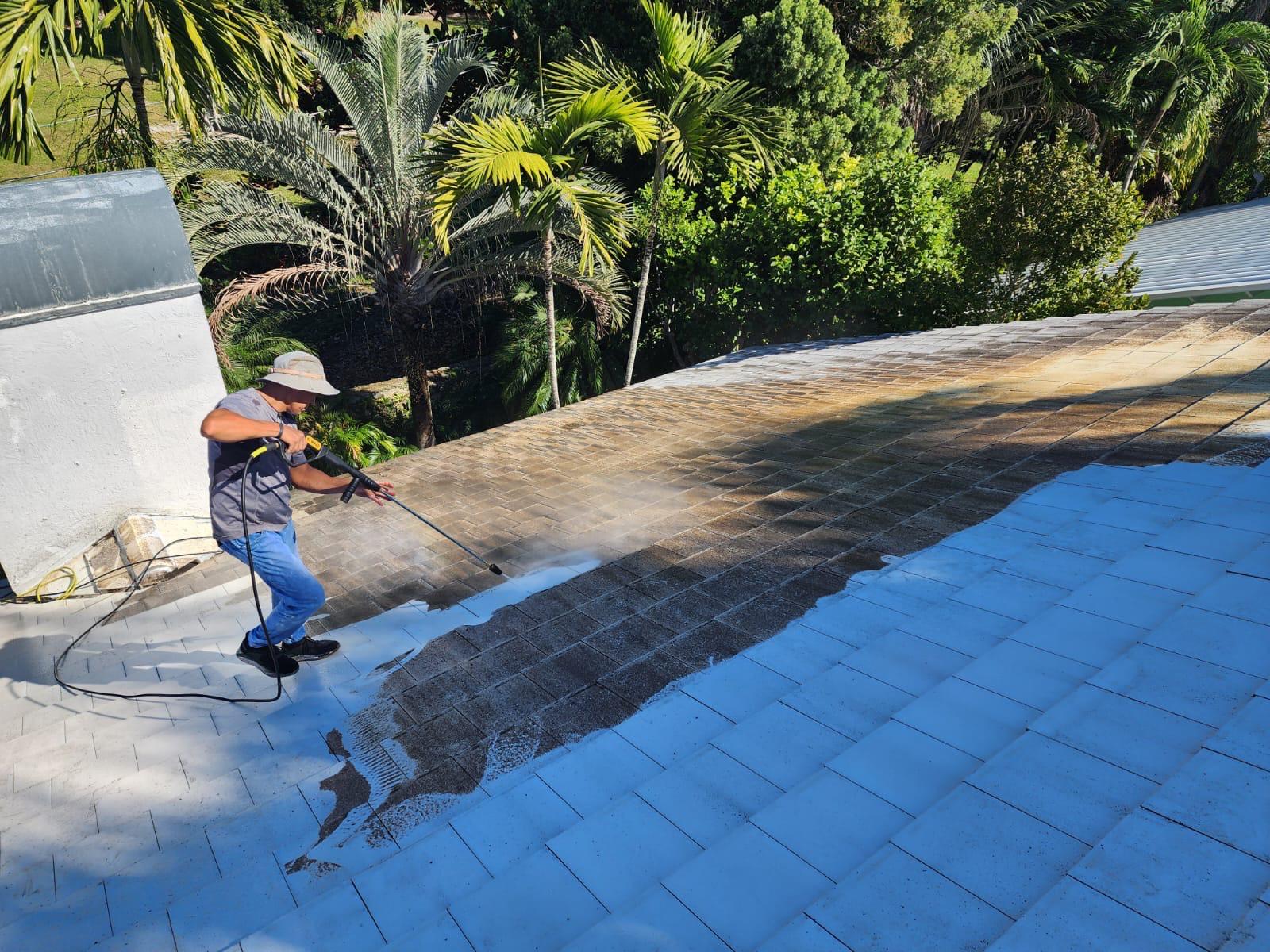 Technician pressure washing a shingle roof in South Florida
