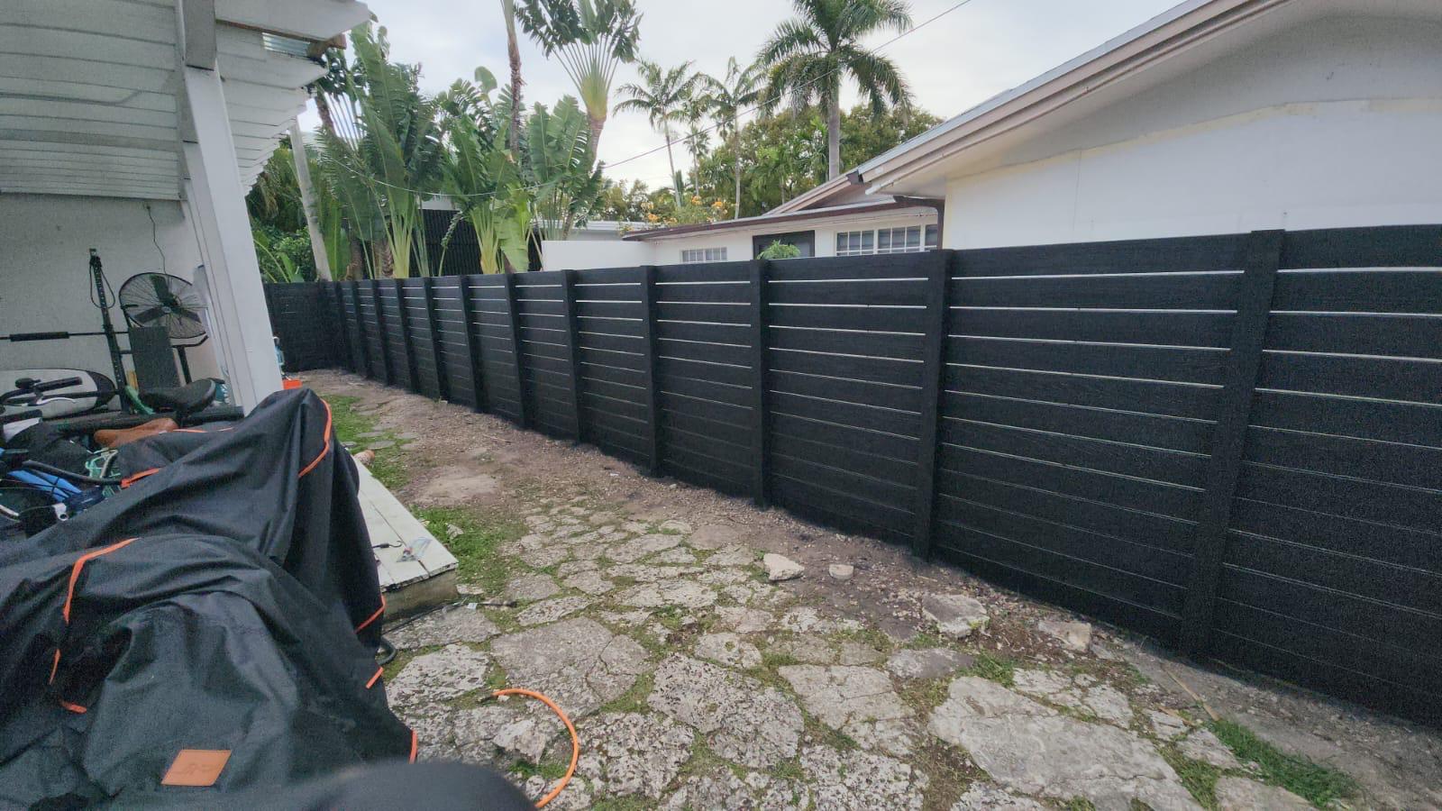 Side-yard horizontal slat fence refinished in solid black
